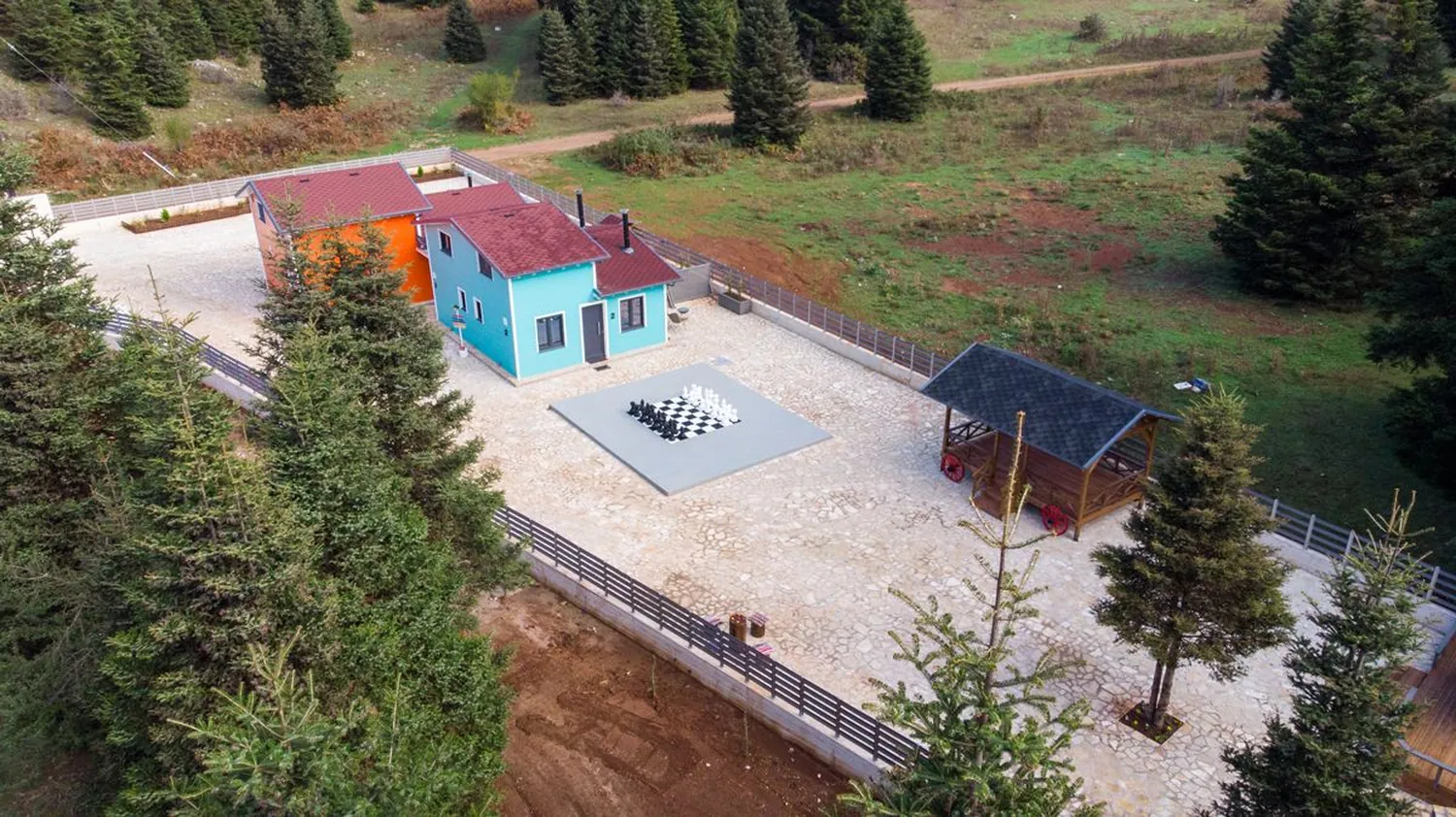Τα δύο σπίτια και η πέτρινη αυλή από ψηλά, μέσα στο ελατόδασος